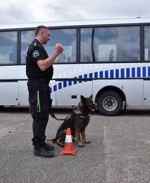 Policjant z psem służbowym przed przeszukiwaniem autokaru.
