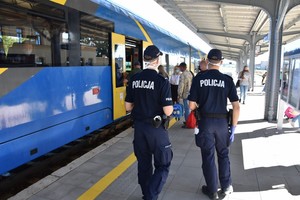 Policjanci na peronie oczekują na możliwość wejścia do pociągu.