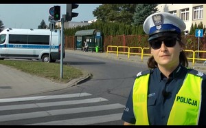 Policjantka stoi przy przejściu dla pieszych z sygnalizacją świetlną.