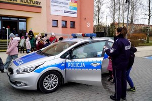 Policjantka pokazuje dzieciom radiowóz policyjny.