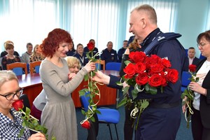 Uroczystość w auli Komendy Powiatowej Policji w Starogardzie Gd. Komendant składa życzenia wręczając różę.