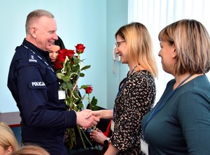 Uroczystość w auli Komendy Powiatowej Policji w Starogardzie Gd. Komendant składa życzenia wręczając różę.
