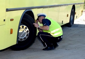 Zdjęcie poglądowe. Policjant kontroluje stan techniczny autokaru.