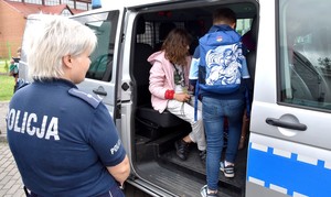 Policjantka z dziećmi przy radiowozie.