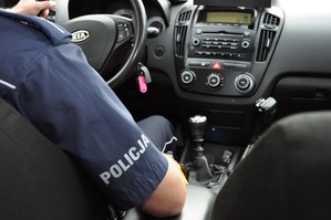 Policjant siedzi za kierownicą radiowozu.