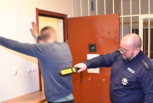Policjant przeszukuje zatrzymanego mężczyznę.