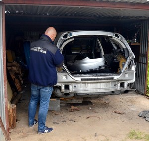 Technik prowadzi oględziny odzyskanego mercedesa.