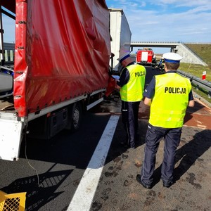 Policjanci na miejscu wypadku prowadzą oględziny rozbitych pojazdów.