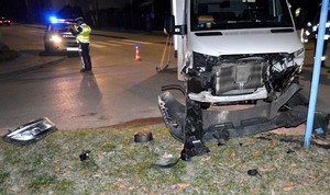 Policjant prowadzi oględziny rozbitego mercedesa. W centrum zdjęcia widać całkowicie zniszczony przód auta.