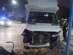 Policjant prowadzi oględziny rozbitego mercedesa. W centrum zdjęcia widać całkowicie zniszczony przód auta.