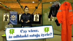 Policjantka w policyjnej strzelnicy opowiada o odblaskach. W dolnej części kadru napis: Czy wiesz, że odblaski ratują życie?