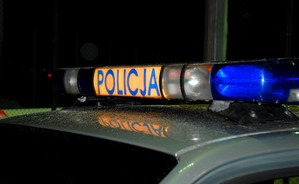 Zapalona na dachu radiowozu galeria z napisem POLICJA, na tle nocnego nieba.