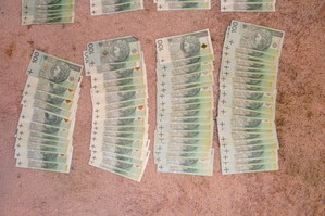 Rozłożone na dywanie banknoty 100 złotowe, przygotowane do procesowego zabezpieczenia.