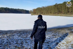 Policjant stoi na brzegu zamarzniętego jeziora.