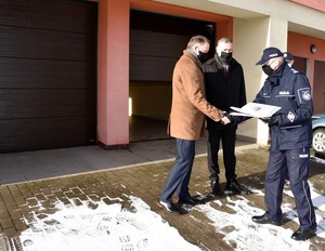 Komendant dziękuje burmistrzowi Czarnej Wody. W tle wymienione drzwi wjazdowe do garaży posterunku.