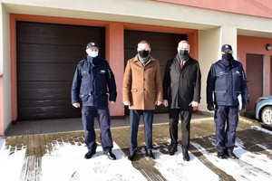 Wszyscy uczestnicy spotkania w zdjęciu grupowym na tle wymienionych bram garażowych.