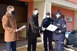 Komendant dziękuje wójtowi gminy Kaliska. W tle wymienione drzwi wjazdowe do garaży posterunku.
