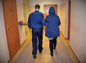 Policjant prowadzi podejrzaną.