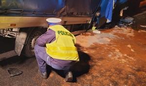 Policjant kuca w czasie oględzin tylnego koła rozbitego Iveco.
