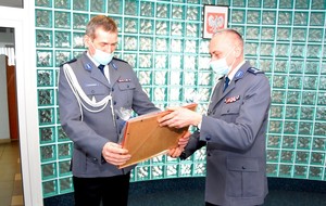 Komendant KPP w Starogardzie Gdańskim przekazuje swojemu zastępcy drobny upominek.