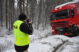 Technik kryminalistyki wykonuje zdjęcie uszkodzeń w uczestniczącym w wypadku dafie.
