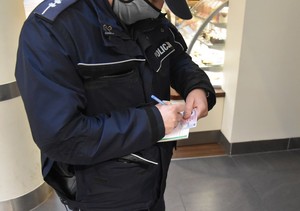 Policjant wypisuje mandat karny.
