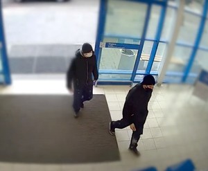 Obraz z kamery przedstawiający wizerunki podejrzanych mężczyzn wchodzących do sklepu.