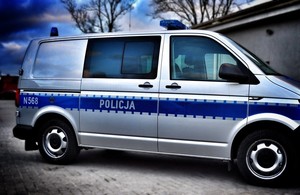 Policyjny vw t6 zaparkowany w pobliżu bramy garażowej.