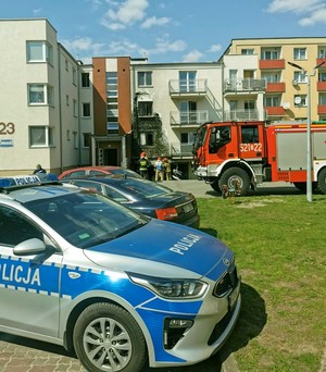 Radiowóz policyjny na tle ugaszonego budynku.