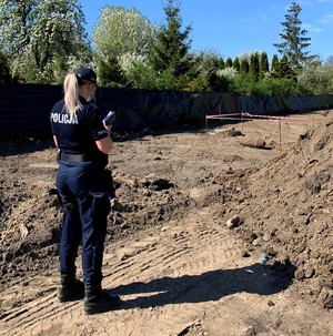 Policjantka opisuje w notatniku służbowym leżący w pobliżu niewybuch.