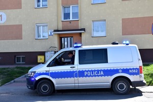 Radiowóz policyjny, a w tle stojący blok.