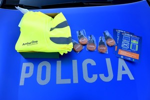 Rozłożone na masce policyjnego radiowozu kamizelki, ulotki oraz ledowe bryloczki.