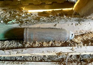 Leżący na strychu pocisk artyleryjski o długości ok. 40 cm oraz średnicy około 10 cm.
