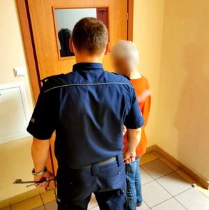 Policjant prowadzi zatrzymanego.