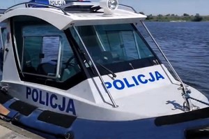 Policyjna motorówka na wodzie przycumowana do brzegu.