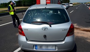 Policjant prowadzi oględziny rozbitej toyoty.