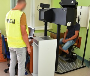 Policjant doprowadził podejrzanego do technika kryminalistyki w celu pobrania odcisków palców.