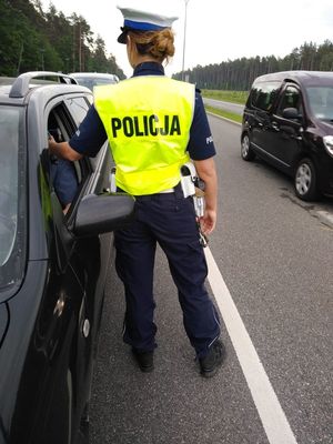 Policjantka stoi przy kontrolowanym pojeździe.