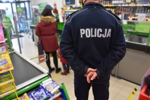 Policjant w sklepie sprawdza przestrzeganie obostrzeń cowidowych przez klientów.