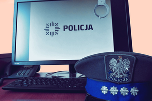 Zdjęcie poglądowe. Policyjna czapka, a w tle monitor komputera z tapetą ukazującą logo policji.