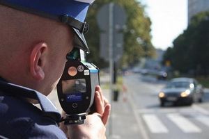 Policjant z radarem mierzy prędkość nadjeżdżającego auta.