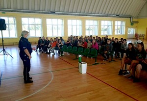 Policjantka na sali gimnastycznej w czasie zajęć z młodzieżą szkolną.