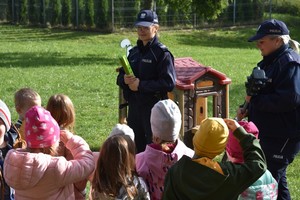 Policjantka prezentuje dzieciom opaski odblaskowe.