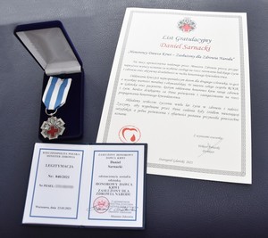 Zdjęcie medalu, dyplomu oraz legitymacji zasłużonego honorowego dawcy krwi.