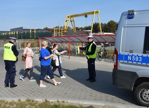 Policjanci wręczają opaski odblaskowe pieszym udającym się do pracy.