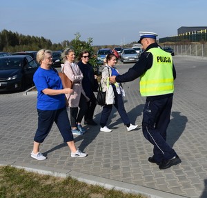 Policjanci wręczają opaski odblaskowe pieszym udającym się do pracy.