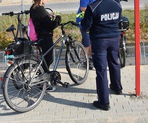 Policjanci wręczają opaski odblaskowe rowerzystom udającym się do pracy.