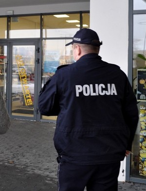 Policjant przed wejściem do sklepu, gdzie przeprowadzi kontrolę przestrzegania obowiązujących przepisów.