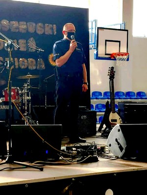 Dzielnicowy ze Skarszew przemawia ze sceny do seniorów, uczestników imprezy.