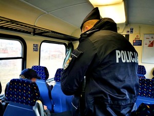 Policjanci kontrolują czy pasażerowie pociągu mają zasłonięte usta i nos w czasie podróży.